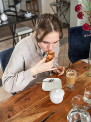 The girl drinks coffee and eats a croissant.