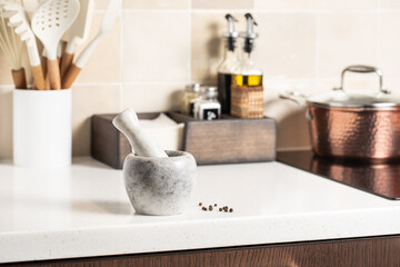 Marble mortar with pestle. Stylish bright kitchen in the background.