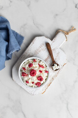 Obraz na płótnie Canvas Fresh cottage cheese with raspberries in a bowl on a white background