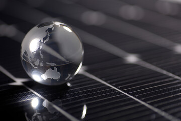 ソーラーパネルに置いたガラスの地球 - obrazy, fototapety, plakaty