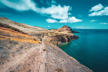 Fototapeta na wymiar Sporty woman hikes along hike trail with scenic view on the beautiful foothills of the Madeiran island. São Lourenço, Madeira Island, Portugal, Europe.