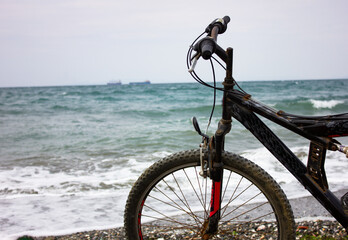 Mountain bike on the beach and wavy sea view on background. Conceptual bicycle and sea image with copy space. Bike on beach sands.