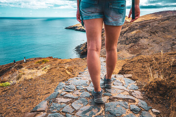 Legs of sporty woman walking on a paved hiking trail with picturesque view in the beautiful...