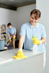 Cleaning service workers doing housework in team, woman using detergent to wipe dust with rag from...