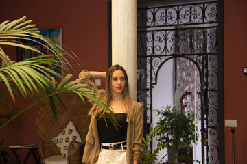 Young and beautiful blonde Latin woman is leaning against a marble column in the inner courtyard of a hotel. The woman is sad and pensive with anguish. Concept depression and stress.