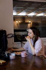 Young beautiful asian girl blogger working at computer at home, eating sandwiches, drinking coffee