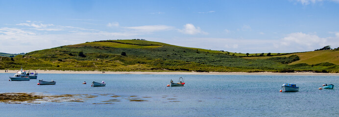 Several small boats are anchored in Clonakilty Bay on a sunny day. Blue sky with white clouds over the beautiful Irish coast. boat on body of water