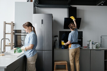 Professional cleaning workers wiping dust from furniture while doing housework in team in the...