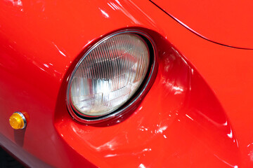 Close-up of the round headlamps of a red, sport classic car. Beautifully restored details of a...