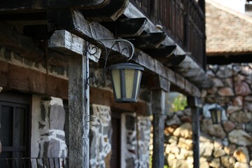 A hanging lantern in front of the house on a wooden beam