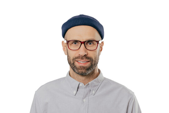 Headshot of stylish unshaven man with glasses, headgear, formal shirt, looks at camera, isolated on white. Caucasian male in fashionable outfit