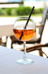 Close up of a glass of aperol spritz or campari orange cocktail with orange slice and ice on a restaurant table on the seashore on a sunny day. Holiday concept. Summer cocktail, live photo