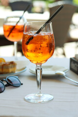 A glass of aperol spritz or campari orange cocktail with orange slice and ice on a restaurant table on the seashore on a sunny day. Holiday concept. Summer cocktail, live photo, vacation mood