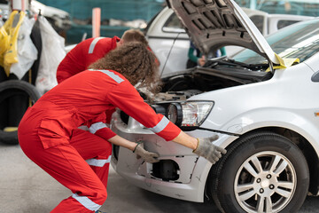 Mechanic man in red uniform installing front skirt at auto car garage service. Automobile technician working repair and maintenance car workshop center.