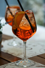 Two glasses of aperol spritz or campari orange cocktail with orange slice and ice on a restaurant table. Holiday concept. Live photo of having a glass of summer cocktail in vacation