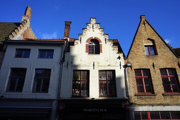 Schmale restaurierte Fassaden alter Häuser mit Treppengiebel vor blauem Himmel im Sonnenschein in...