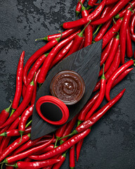 Sauce with cranberries and hot peppers. Round jar of red sauce in center of oval wooden plank on...