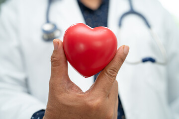 Doctor holding a red heart in hospital ward, healthy strong medical concept.