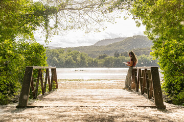 Landscape with a bridge and a lake on the background and a young woman writing