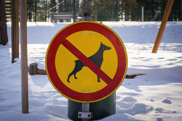 No dogs allowed sign next to a playground in winter