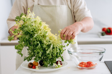 a woman prepares a healthy diet vegetable salad with tomatoes, mozzarella cheese, green salad, olive oil and balsamic