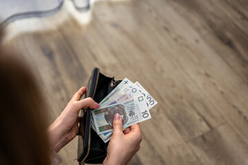 woman checking Polish złoty banknotes. She appears to be focused and attentive, suggesting the...