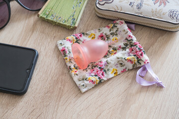 menstrual cup on a table at home next to sunglasses, purse and personal items.
