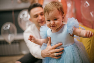 Family portrait. A little girl in a princess dress with a young dad is happy on her first birthday.