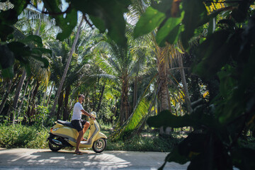 A man on a motorcycle in palm trees on a tropical island