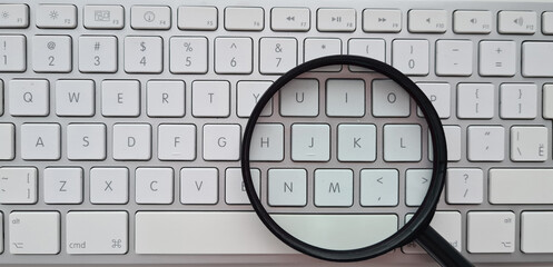 Magnifying glass on computer keyboard closeup. Searching for information