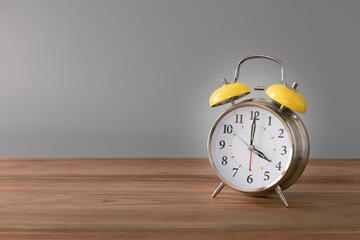 Retro silver alarm clock. 4:00.  am,  pm. Neutral background. Brown wood surface. Horizontal  photography with empty space for text or image.