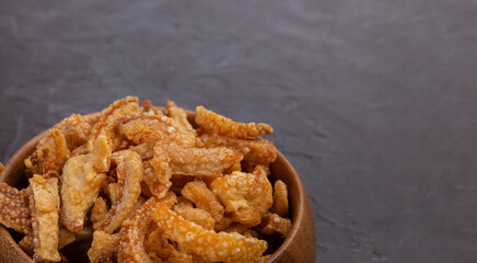 
Crispy Pork Belly Chicharron (torresmo)  is a popular dish in Spain and Latin America. Bowl of Fried Pork Skins on dark background
