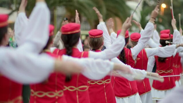 Parade festival participants. Traditional celebration of dancing and music on the street of the city. Beautiful women in red dresses dances a folk dance. Unrecognizable people