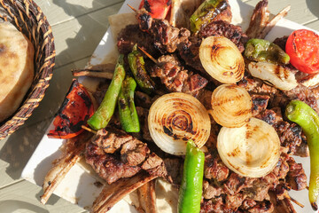 Top view delicious mixed kebab meat chopsteak meatball skewer lamb with vegetables pepper tomato onion near bread. Selective focus of area.