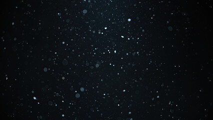 White snow falling on an isolated black background, bokeh of flying snowflakes, dust particles or...