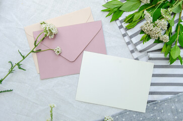 Blank cards and craft rose envelope, seasonal herbs on the cotton tablecloth. Creative rustic invitation card, top view.