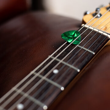 Green Guitar Pick in Strings of Electric Guitar