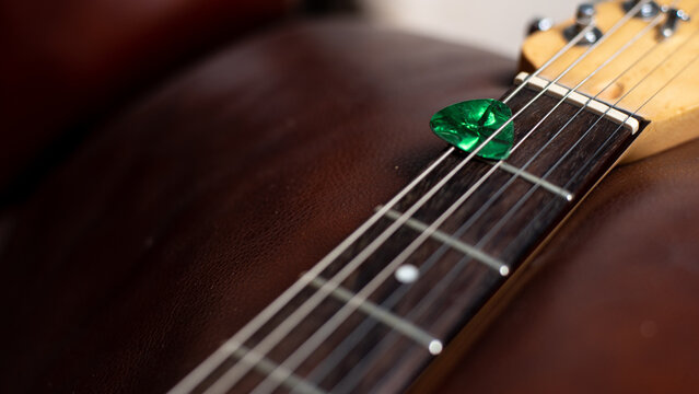 Green Guitar Pick in Strings of Electric Guitar