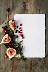 Invitation card with wood background, cotton paper, promeganates, cuted figs and lavander 