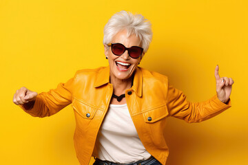 smiling grandmother with sunglasses doing poses on a studio with yellow background