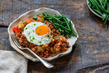 Corned beef hash with fried egg and green beans - obrazy, fototapety, plakaty