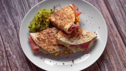 A plate of food with a quesadilla and guacamole on it.