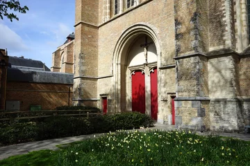 Papier Peint photo Brugges Rote Türen der Sankt Salvator Kathedrale im Stil der Backsteingotik mit Fassade in Beige und Rundbogen als Teil des Unesco Weltkulturerbe in der Altstadt von Brügge in Westflandern in Belgien
