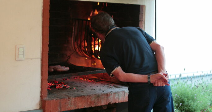 Man preparing barbeque parilla. Casual candid senior person cooking