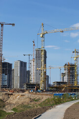 Construction site. Reinforced concrete frames of multi-storey buildings and construction cranes. Against the background of the blue sky.
