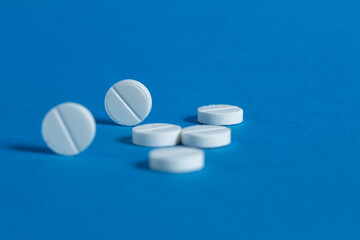 Round white pills, close-up on a blue background