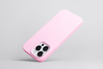 iPhone 14 Pro in pink soft silicone case falls down back view, phone case mockup isolated on grey background