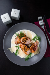 Meat rolls with cheese and mushrooms, creamy sauce, parmesan and herbs in plate.