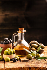 Glass container with olive oil branches and olives on a dark background. vertical image. top view. place for text