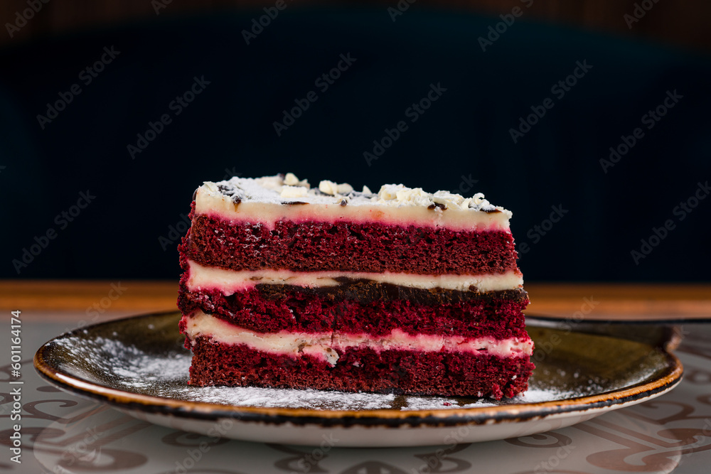 Poster piece of red velvet cake with chocolate and powdered sugar.